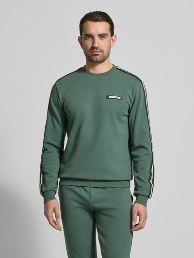 Männermodel trägt Sweatshirt mit Label-Details und Rundhalsausschnitt von EA7 Emporio Armani in Grün, Baumwoll-Mix, Regular-Fit, Ganzkörperansicht von vorne. Rückenlänge bei Größe M 63 cm, Ärmellänge 66 cm.