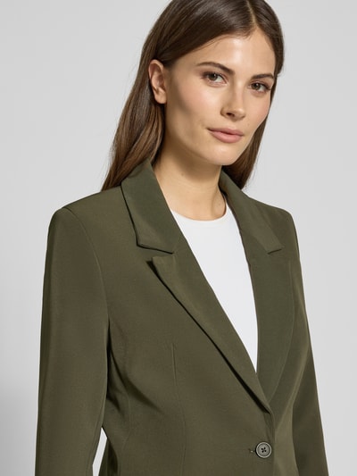 Frauenmodel trägt Slim Fit Blazer mit Pattentaschen Modell 'ISA' von Guido Maria Kretschmer, Olivgrün, Material-Mix mit Stretch-Anteil, Nahaufnahme Oberkörper.