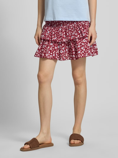 Vrouwenmodel draagt uitlopend dames minirok met all-over bloemenmotief, volantdetails, gesmokte boord, puur katoen, model 'ZOEY' van Only. Nahaufnahme onderlichaam.