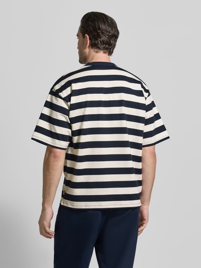 Männermodel trägt Relaxed Fit T-Shirt mit Logo-Stitching Modell 'Beam' von Woodbird aus reiner Baumwolle, Rückansicht, Ganzkörperansicht.