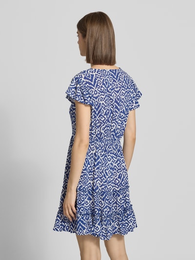 Frauenmodel trägt tailliertes Freizeitkleid aus reiner Viskose Modell 'CLAUDETTE' von Only mit blau-weißem Allover-Muster, Volantsaum, Kurzarm, Mini-Länge, Webware-Struktur, Ganzkörperansicht Rückansicht.