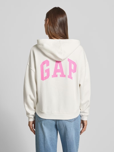 Vrouwenmodel draagt hoodie met logo-print en geribde afsluitingen van GAP, katoenmix, loose fit, capuchon, schouderpartijen, logoprint. Ganzkörperansicht Rückansicht.