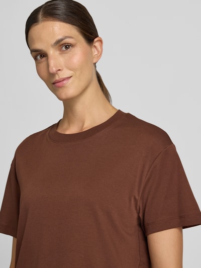 Modelka kobieca ma na sobie damski t-shirt z czystej bawełny od Stefanel, luźny krój, opadające ramiona, okrągły dekolt, długość tyłu w rozmiarze S: 62 cm, zbliżenie na górną część ciała.