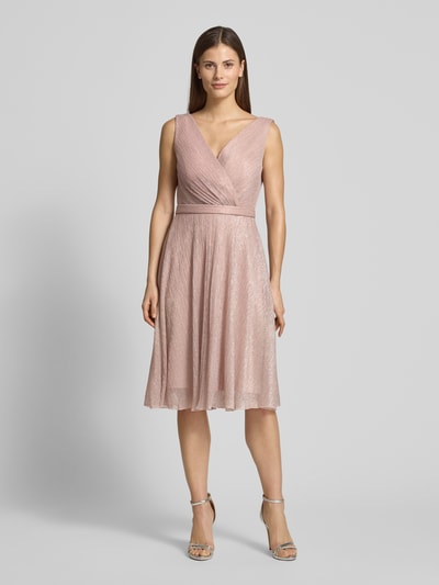Vrouwenmodel draagt knielanges Cocktailkleid mit V-Ausschnitt van TROYDEN COLLECTION, getailleerde fit, glanzende stof, tailleband, knielengte, voorkant vollichaamsaanzicht.