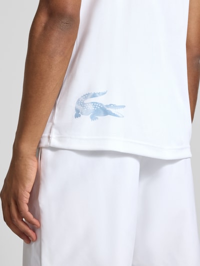 Männermodel trägt Regular Fit Sport-T-Shirt im Colorblock-Design von Lacoste Sport in Weiß mit blauem Logo, Nahaufnahme Oberkörper.