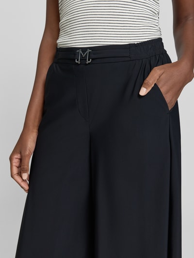 Frauenmodel trägt Hose in verkürzter Passform mit Gürtel Modell 'Pia' von MAC in Schwarz, Material-Mix mit Stretch, Nahaufnahme Oberkörper.