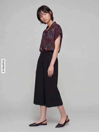 Frauenmodel trägt schwarze Weite Hose aus Viskose-Mix Modell 'MELLI S' von Brax, kombiniert mit dunkler Bluse, Ganzkörperansicht von vorne, Damen Weite Hose von Brax.
