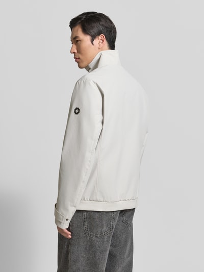 Męski model nosi Regular Fit Funktionsjacke aus wasserdichtem Material Modell 'LUCCA' von Strellson, jasnoszary kolor, długi rękaw, prosty fason, stójka, metalowa aplikacja logo, boczne kieszenie na suwak, krój regular fit, widok całej sylwetki z tyłu.