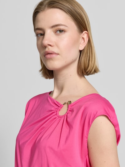Frauenmodel trägt T-Shirt mit asymmetrischem Ausschnitt von Marc Cain in Pink, Zierelement mit Raffungen, Material-Mix, Nahaufnahme Oberkörper.