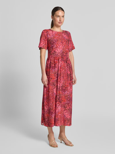 Frauenmodel trägt Midikleid aus Viskose im Allover-Look von Rich & Royal in Rot-Pink Tönen, A-Linie, Rundhalsausschnitt, Ganzkörperansicht von vorne.