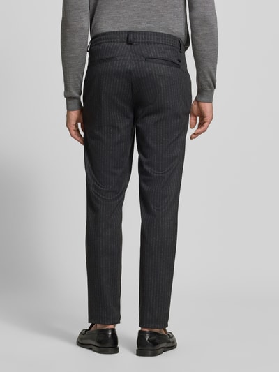 Männermodel trägt Regular Fit Stoffhose mit Viskose-Anteil Modell 'Phil' von Brax, dunkles Allover-Streifenmuster, Ganzkörperansicht Rückansicht.