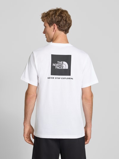 Mannelijk model draagt wit t-shirt met labelprint van Model 'Evolution' van The North Face van katoenmix, regular fit, ruglengte bij maat M 73 cm, labelprint op de achterkant, geheel zichtbare rugaanzicht.