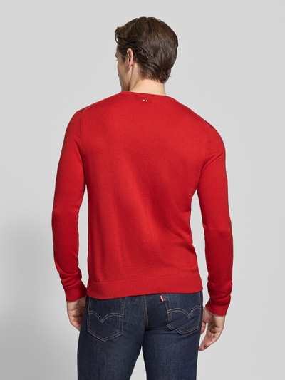 Männermodel trägt sweter wełniany z czystej wełny, krój slim fit, Model 'DAMAVAND' od Napapijri, detal z logo, elastyczne wykończenia, intensywna czerwień, gładka faktura, Długość tyłu w rozmiarze M: 66 cm, Długość rękawów w rozmiarze M: 69 cm, widok całej sylwetki od tyłu.