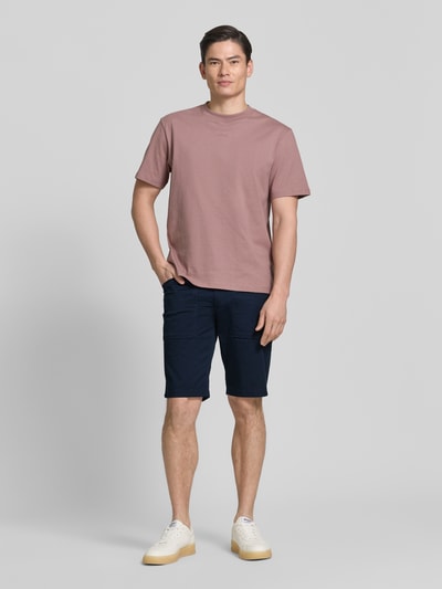 Männermodel trägt Regular Fit Cargoshorts aus Baumwoll-Mix von s.Oliver BLACK LABEL, kolor granatowy, 5 kieszeni, detal label patch, twill, pasek, zapięcie na guzik i kryty zamek, krój regular fit, widok całej sylwetki z przodu