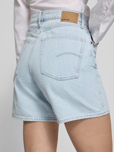Vrouwenmodel draagt Straight Fit Shorts in denimlook model 'Jett' van G-Star Raw, puur katoen, steek- en achterzakken, knoop- en ritssluiting, bandwijdte maat 27: 38 cm, binnenbeenlengte maat 27: 15 cm, lichtblauw, gladde textuur, detailopname achterzijde.