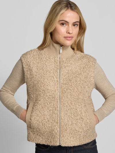 Vrouwenmodel draagt Weste mit Stehkragen Modell 'Guluni' van OPUS, effen beige, grof gestructureerd polyester, rits, zijzakken, close-up bovenlichaam.
