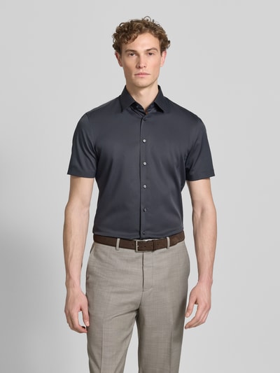 Männermodel trägt Slim Fit Business-Hemd mit Kentkragen von Jake*s in donkergrijs, elastische materiaalmix, knoopsluiting, met korte mouwen, ruglengte bij maat 39/40: 80 cm, schouderbreedte: 45 cm, mouwlengte: 25 cm, overhemden, zakelijk hemd, ganzkörperansicht von vorne.