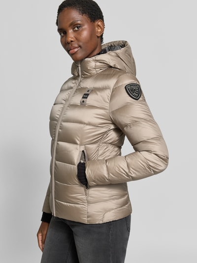 Modelka nosi kurtkę puchową z efektem pikowania, detal z logo, kaptur, krój taliowany, Model 'Charme' od Blauer USA, Długość tyłu w rozmiarze S: 62 cm, szerokość ramion w rozmiarze S: 44 cm, szerokość w klatce piersiowej w rozmiarze S: 43 cm, długość rękawów w rozmiarze S: 62 cm, zamek błyskawiczny dwustronny, widok z przodu cała sylwetka