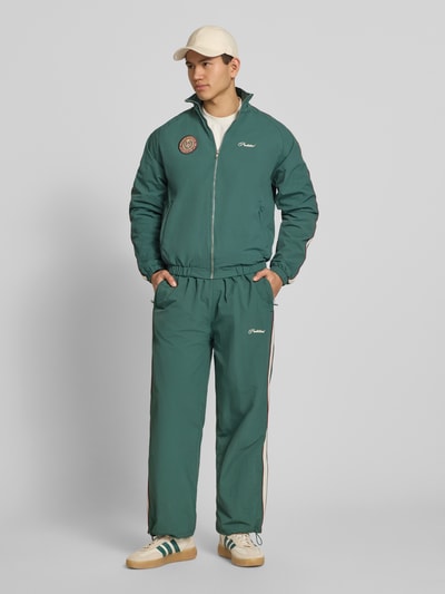 Männermodel trägt Trackpants mit Label-Stitching Modell 'SLIPSTREAM' von PROHIBITED in Grün, Relaxed Fit, Ganzkörperansicht von vorne.