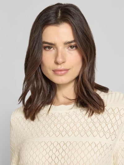 Frauenmodel trägt Regular Fit Pullover aus Viskose-Mix Modell 'Milos' von Vila in Strick-Optik mit Lochmuster, Rundhalsausschnitt, Langärmelig, cremefarbene Textur, Nahaufnahme Oberkörper.