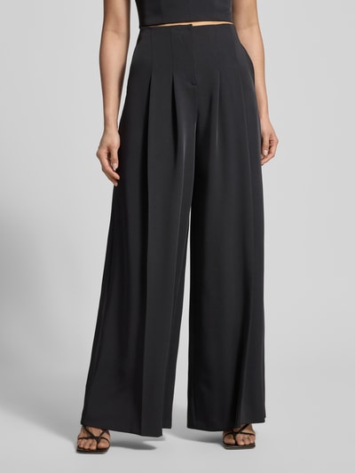 Frauenmodel trägt Stoffhose mit weitem Bein und gelegten Falten von Jake*s Cocktail, Schwarz, Material-Mix mit Stretch, Nahaufnahme Unterkörper, Ganzkörperansicht von vorne.
