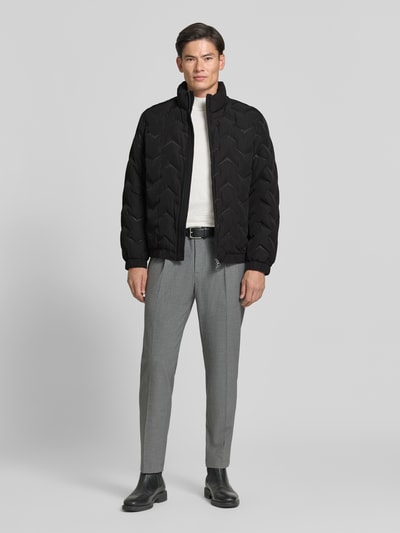 Männermodel trägt Steppjacke mit Stehkragen und Reißverschlusstaschen von Antony Morato in Schwarz, Regular Fit, Ganzkörperansicht von vorne. Rückenlänge 71 cm, Schulterbreite 50 cm, Brustweite 59 cm, Ärmellänge 66 cm.