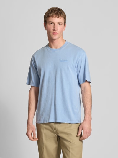 Männermodel trägt T-Shirt mit Rundhalsausschnitt und Label-Stitching von Dickies in Hellblau, Regular Fit, reine Baumwolle, Ganzkörperansicht von vorne.