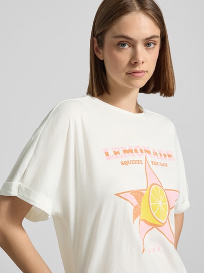 Frauenmodel trägt Damen T-Shirt Boxy Fit T-Shirt aus reiner Baumwolle Modell 'MINNA' von Only, Optik: Unifarben, Motiv-Print auf der Front, Rundhals, Kurzarm mit fixiertem Umschlag, Rollsaum, Jersey, reine Baumwolle, Farben Weiß mit gelbem und rosa Print, Nahaufnahme Oberkörper.