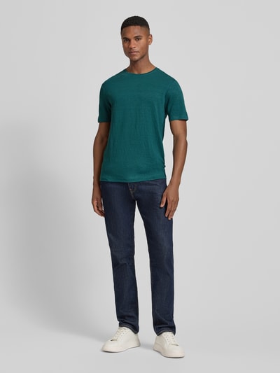 Männermodel trägt T-shirt aus leinen-elastaan-mix met ronde hals van OLYMP Level Five, regular fit, labeldetail, ruglengte maat M 69 cm, ganzlichaamsaanzicht van voren.