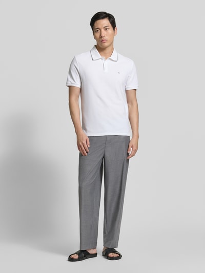 Männermodel trägt Jog Pants mit französischen Eingrifftaschen Modell 'YROWAY' von American Vintage, Straight Fit, Material-Mix mit Viskose-Anteil, elastischer Bund, dezentes Karomuster, hellgraue Farbe, Ganzkörperansicht von vorne.