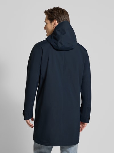 Męski model nosi granatową Parka z patkami przy mankietach Didriksons, model 'GEORGE', krój regular fit, kaptur, długi rękaw, długość tyłu w rozmiarze M: 94 cm, szerokość ramion w rozmiarze M: 45 cm, szerokość klatki piersiowej w rozmiarze M: 55 cm, długość rękawów w rozmiarze M: 67 cm, całkowity widok z tyłu
