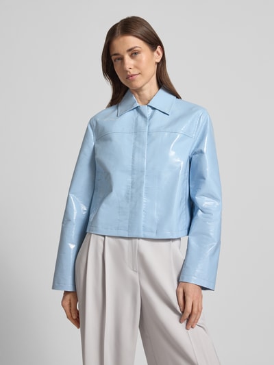 Frauenmodel trägt Jacke in glänzender Lackleder-Optik - curated by Vicky Heiler von SIC in Hellblau, Boxy Fit, Umlegekragen, Eingrifftaschen, glatte Oberfläche, ganzkörperansicht von vorne, Rückenlänge 50 cm, Schulterbreite 41 cm, Brustweite 52 cm, Ärmellänge 60 cm.
