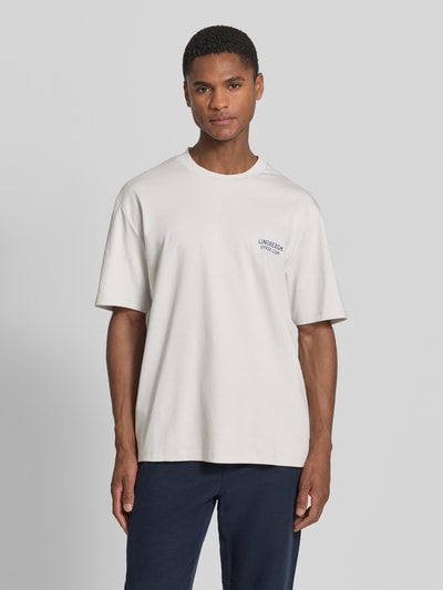 Männermodel trägt Oversized T-Shirt mit Label-Print von Lindbergh in Weiß, Reine Baumwolle, Rundhalsausschnitt, Rückenlänge 70 cm, Ganzkörperansicht von vorne.