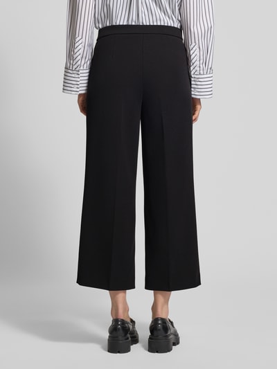 Frauenmodel trägt Hose mit verkürzter Passform Modell 'Hillda-650' von STEHMANN aus Material-Mix mit Stretch-Anteil, Bügelfalten, Ganzkörperansicht Rückansicht.
