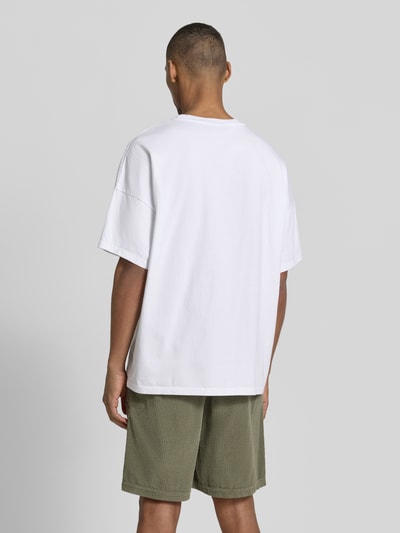 Männermodel trägt weißes T-Shirt mit Rundhalsausschnitt Modell 'FIZVALLEY' von American Vintage, lockerer Schnitt, Rückenansicht, Ganzkörperansicht Rückansicht.