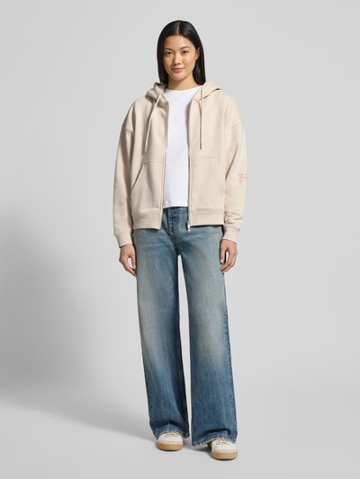 Frauenmodel trägt Oversized Sweatjacke mit Kapuze von Smith and Soul, Baumwoll-Mix, Tunnelzug, Reißverschluss, Eingrifftaschen, gerippte Abschlüsse, helle neutrale Töne, Ganzkörperansicht von vorne.
