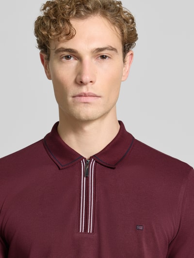 Männermodel trägt Slim Fit Poloshirt mit Reißverschluss von Christian Berg Men aus reiner Baumwolle in Burgunder, Nahaufnahme Oberkörper.