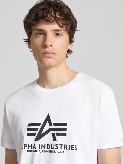 Männermodel trägt weißes T-Shirt mit Logo und Rundhalsausschnitt von Alpha Industries, reine Baumwolle, Regular Fit, Nahaufnahme Oberkörper