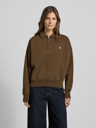 Kobiece model nosi bluzę Sweatshirt mit Label-Stitching od Polo Ralph Lauren, mieszanka bawełny, luźny krój, kołnierzyk polo, krótki zamek błyskawiczny, wyhaftowane logo, prążkowane wykończenia, kolor brązowy, faktura gładka, widok całej sylwetki z przodu.