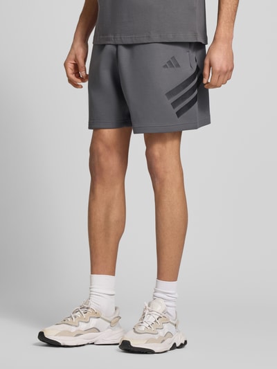 Männermodel trägt Regular Fit Sweatshorts mit Baumwoll-Anteil von adidas Sportswear, Optik: Unifarben, Logo-Print, Sweat, Nahaufnahme Unterkörper.
