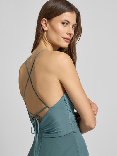 Frauenmodel trägt Maxikleid in Wickel-Optik mit rückseitiger Schnürung von Jake*s Cocktail, Material-Mix mit Stretch-Anteil, Nahaufnahme Rückansicht.