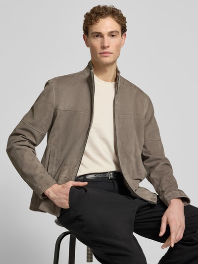 Männermodel trägt taupefarbene Regular Fit Lederjacke aus echtem Ziegenvelours Modell 'JIMMY-S' von Strellson, Stehkragen, Reißverschluss, unifarben, Velours-Textur, Ganzkörperansicht von vorne.