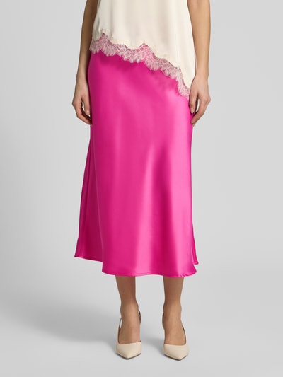 Frauenmodel trägt Midirock mit elastischem Bund Modell 'YASPELLA' von YAS aus Elastischer-Material-Mix in A-Linie, pink glänzend, Nahaufnahme Unterkörper.
