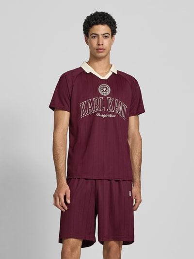 Männermodel trägt Regular Fit T-Shirt mit Logo-Stitching Modell 'Heritage' von KARL KANI, in Bordeaux mit Umlegekragen, Herren T-Shirt, Ganzkörperansicht von vorne. Rückenlänge bei Größe M: 70 cm.