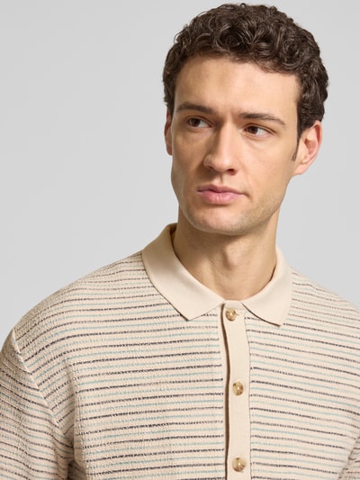 Männermodel trägt Relaxed Fit Poloshirt aus reiner Baumwolle von JOOP!, beige mit braunen und schwarzen Streifen, Crinkle-Textur, Nahaufnahme Oberkörper.
