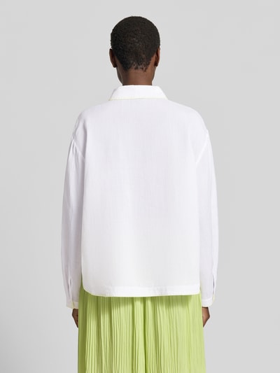 Frauenmodel trägt Bluse aus Ramie mit Brusttasche von Marc Cain in Weiß mit Kontrastkante, Hemdblusenkragen, Ganzkörperansicht Rückansicht. Rückenlänge bei Größe 36: 62 cm, Ärmellänge bei Größe 36: 57 cm, Loose Fit.