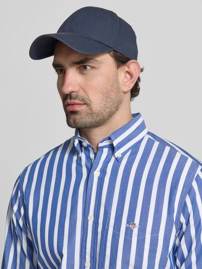 Männermodel trägt Slim Fit Freizeithemd mit Brusttasche von Gant, blauwe en witte strepen, katoen, logo, button-down kraag, nahaufnahme oberkörper.