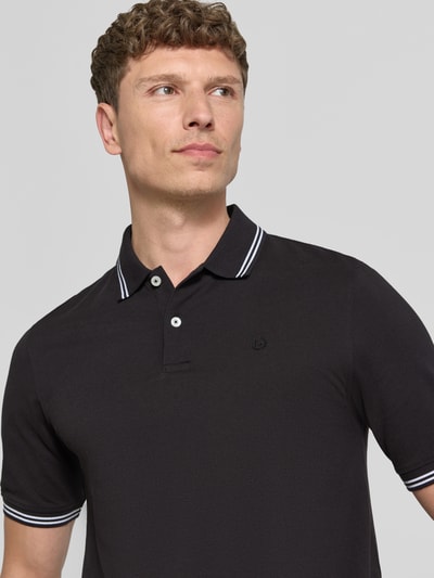 Männermodel trägt Regular Fit Poloshirt mit Logo-Stitching von bugatti, schwarze Baumwolle, Polokragen, Nahaufnahme Oberkörper.