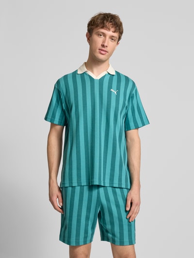 Männermodel trägt Relaxed Fit Poloshirt mit Label-Stitching Modell 'CLASS' von PUMA, Baumwoll-Mix, grüne Streifen, Kontrastkragen, Ganzkörperansicht von vorne.