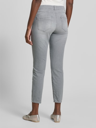 Frauenmodel trägt Slim Fit Jeans aus Baumwoll-Mix Modell 'SHAKIRA' von Brax in grauer Denim-Optik mit Label-Patch und Gürtelschlaufen, Ganzkörperansicht Rückansicht.